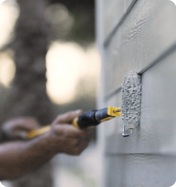 paint contractor painting outside of house with roller
