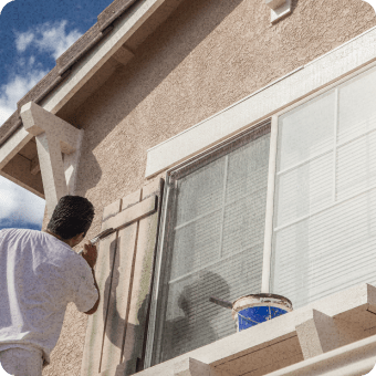 painting contractor painting shutters on residential home